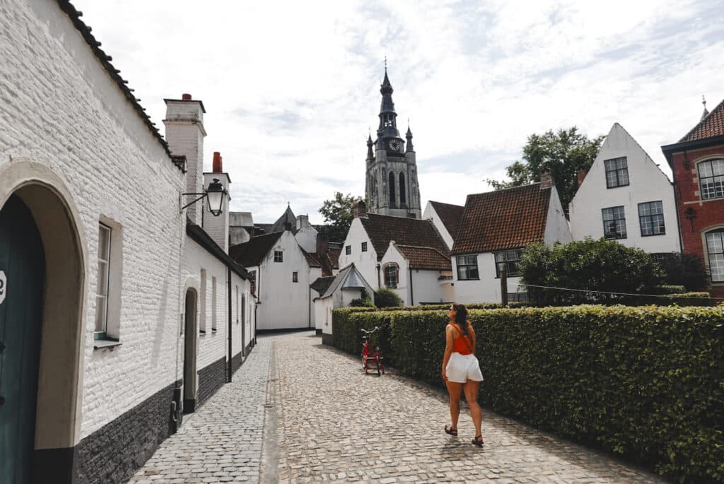 Lotte loopt door het begijnhof van Kortrijk met de Sint-Maartentoren op de achtergrond.
