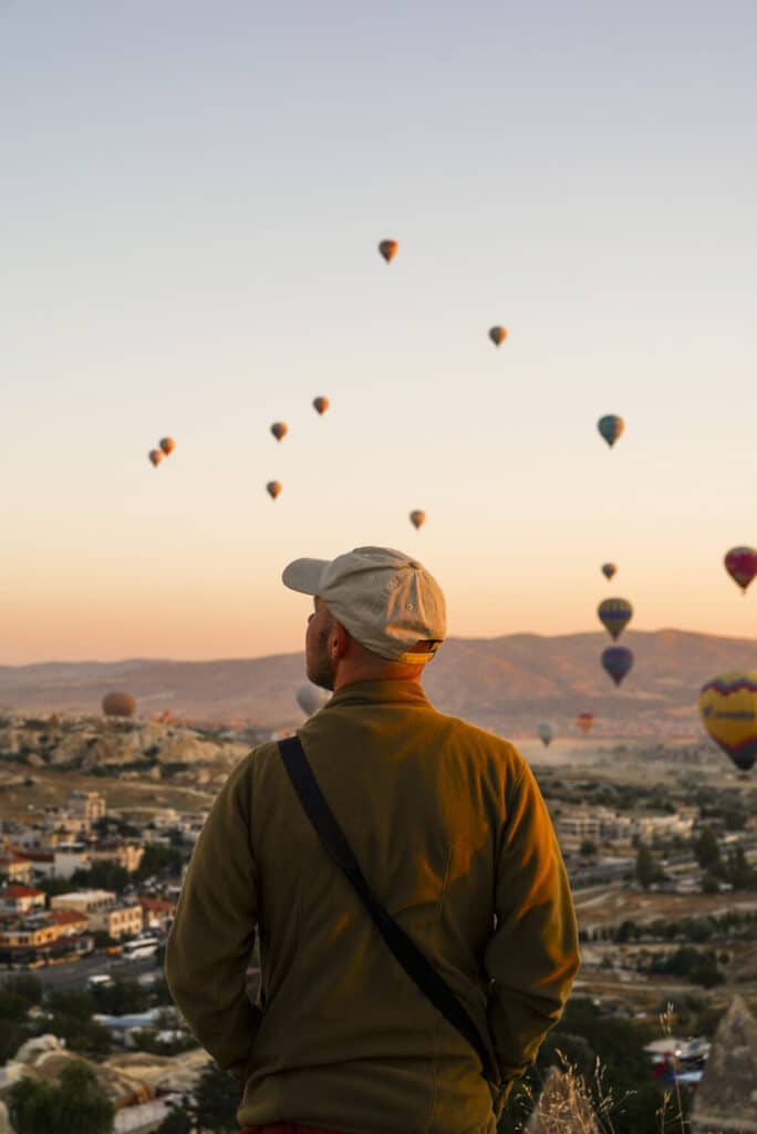 Davo kijkt naar de luchtballonnen die over de Göreme, Cappadocië vliegen, Turkije.