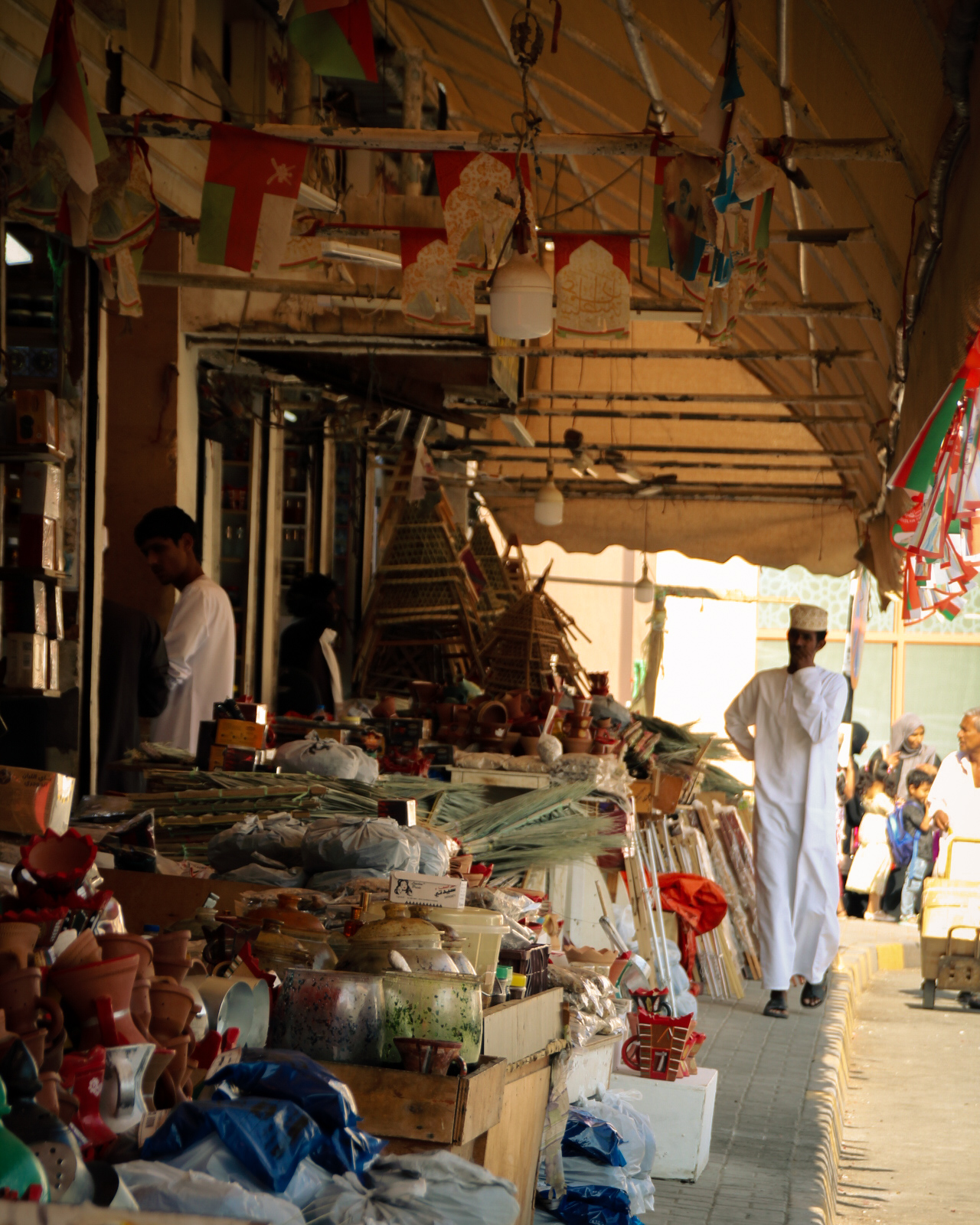 Inwoner van Oman wandelt in traditionele kledij langs de winkels aan de souks van Muscat, Oman.