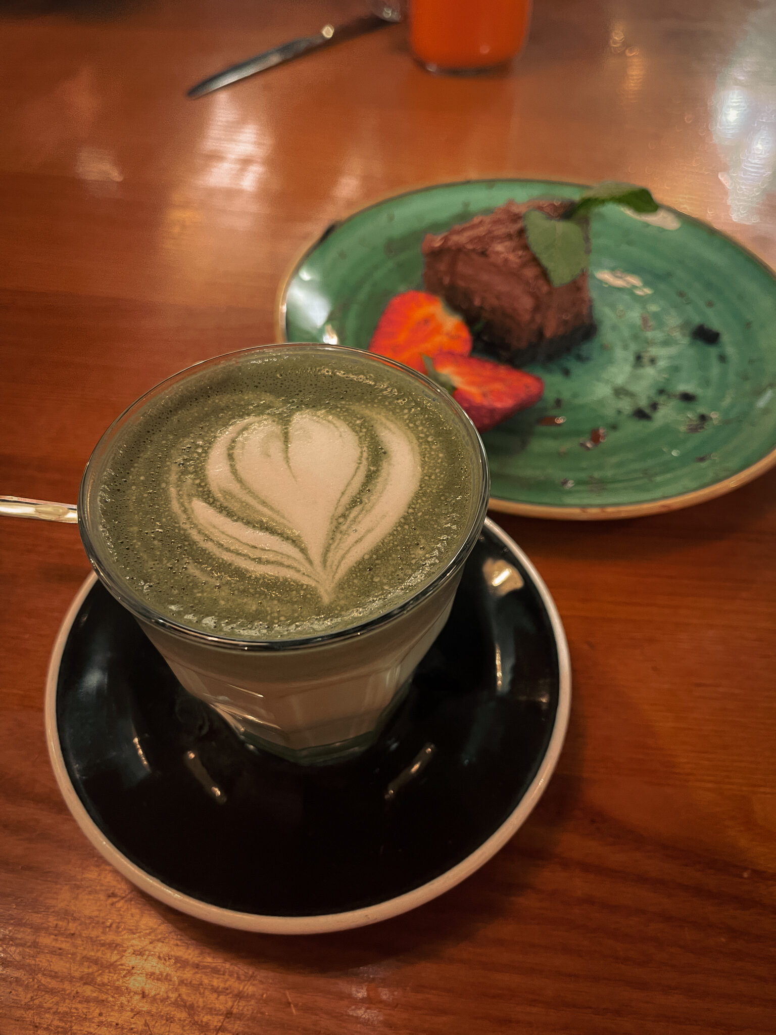 Groene latte macha en een stuk chocoladetaart met een aardbei op in Madrid, Spanje.