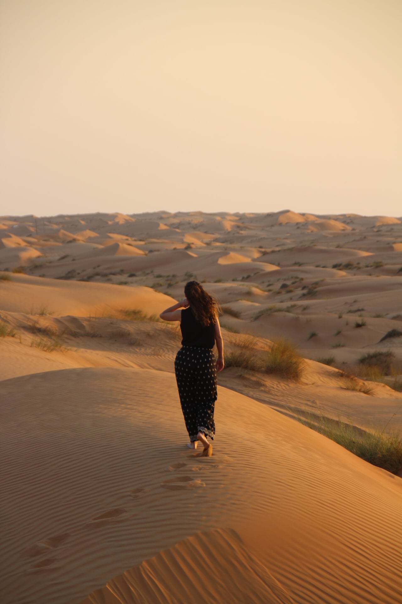 Lotte loopt de zonsondergang tegemoet in de duinen van Wahiba Sands, Oman.